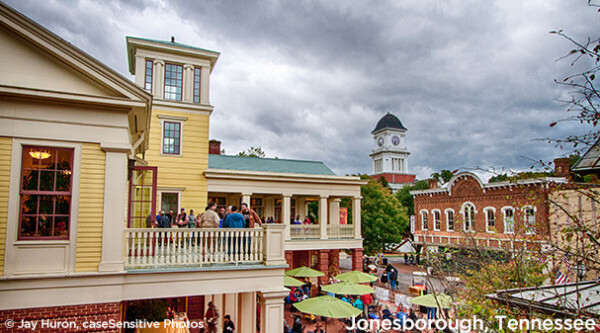 Photo of yellow historic building with rooftop deck where people are gathering.