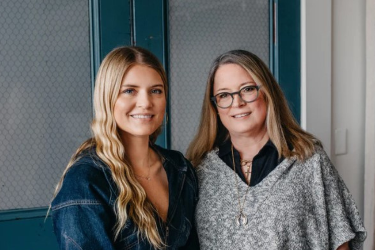 Foto de dos mujeres sonrientes delante de una puerta azul.